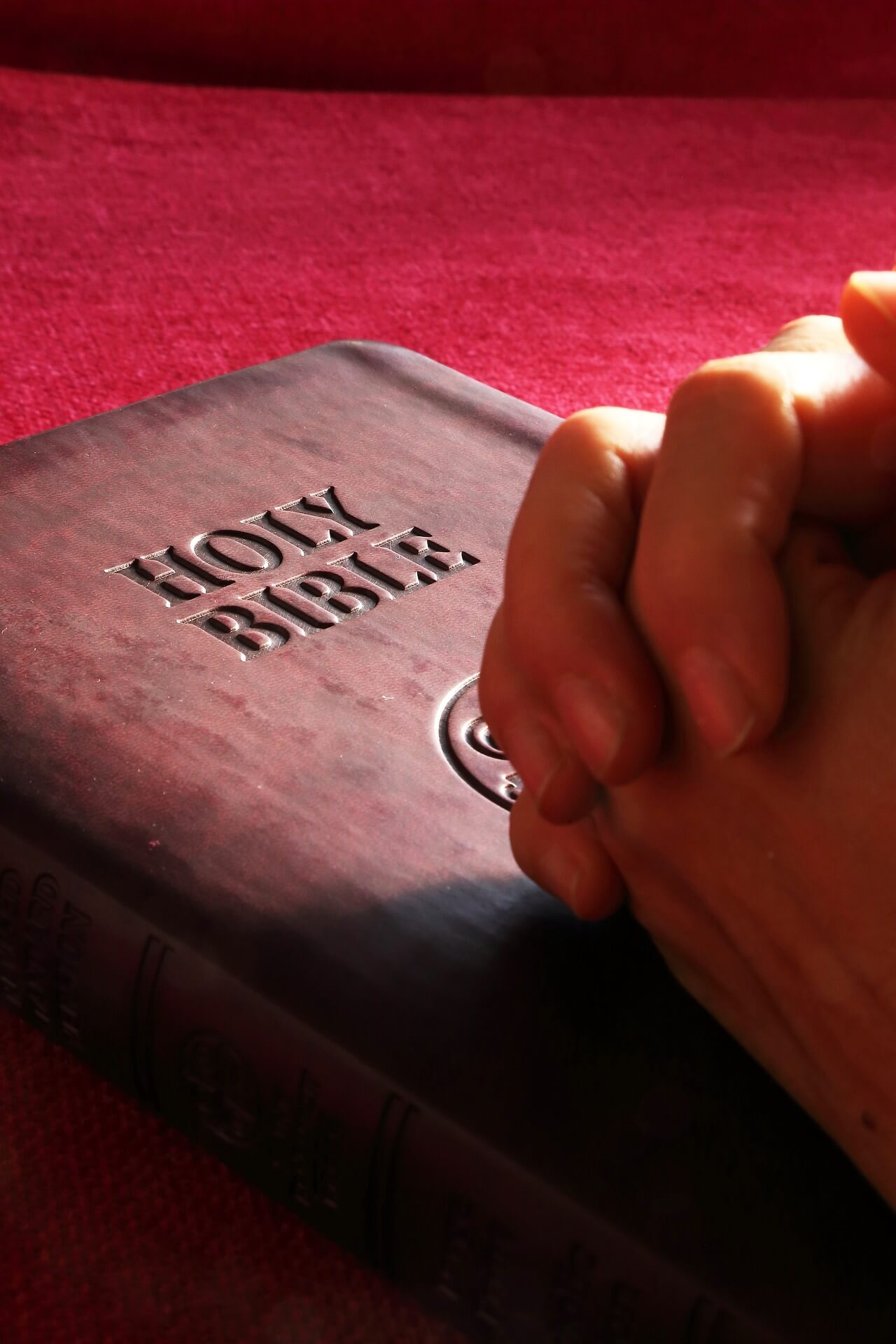 مقدس کتاب و دعا کرنے والے ہاتھوں کی تصویر